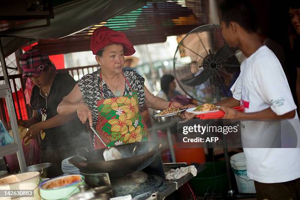 By Dan Martin This photograph taken on February 23, 2012 shows Soon Chuan Choo passing char kway teow to a customer in Georgetown, the state of...