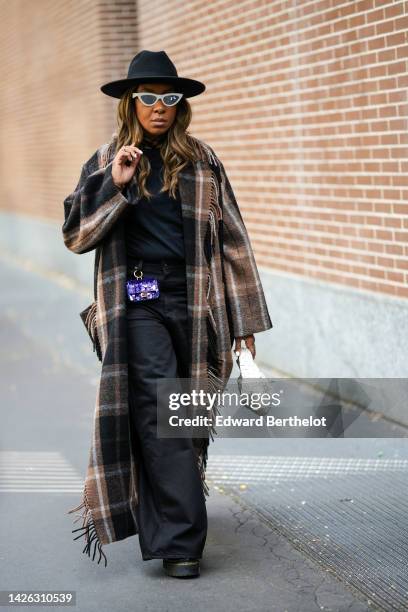 Guest wears a black felt hat, white sunglasses, a black t-shirt, black wide legs pants, a black and brown checkered print pattern wool / fringed long...