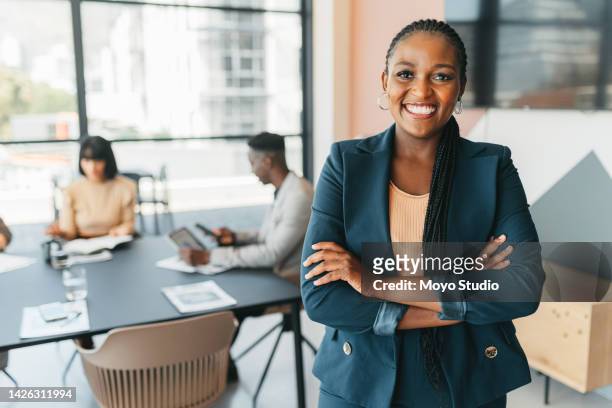 african leader, manager and ceo with a business woman in the office with her team in the background. portrait of a female boss standing arms crossed at work during a meeting for planning and strategy - black business woman bildbanksfoton och bilder