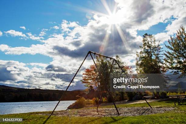 18 year old girl swinging near jericho lake in berlin, new hampshire during autumn - lake solitude (new hampshire) fotografías e imágenes de stock