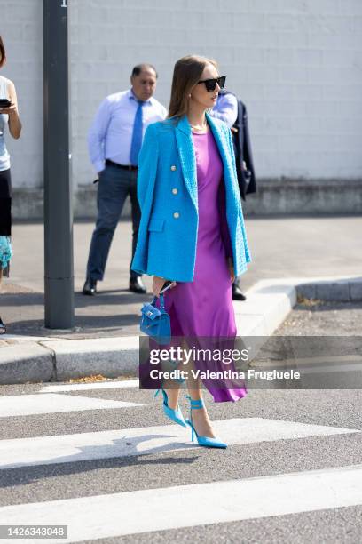 Guest is seen wearing a purple dress and blue jacket, bag and shoes outside Prada show during the Milan Fashion Week - Womenswear Spring/Summer 2023...