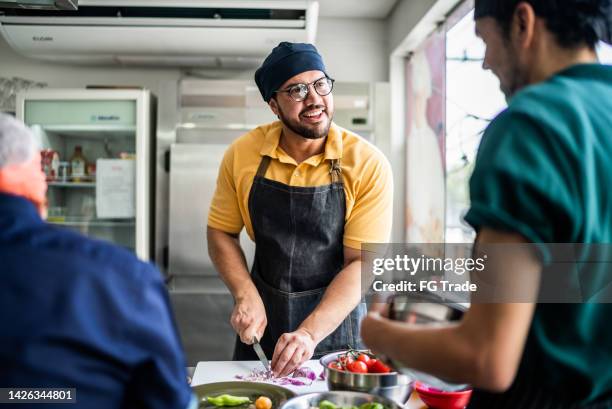 colleagues during cooking class or working in a restaurant - restaurant workers kitchen stock pictures, royalty-free photos & images