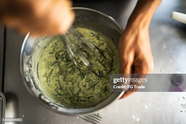 mains féminines mélangeant des ingrédients dans un bol à mélanger - chef cuisinier sauce photos et images de collection