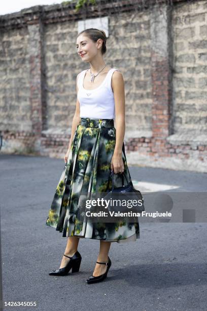 Jenny Walton is seen wearing a printed Prada pleated skirt, a white Prada tank top, Prada black bag and vintage necklace outside Prada show during...