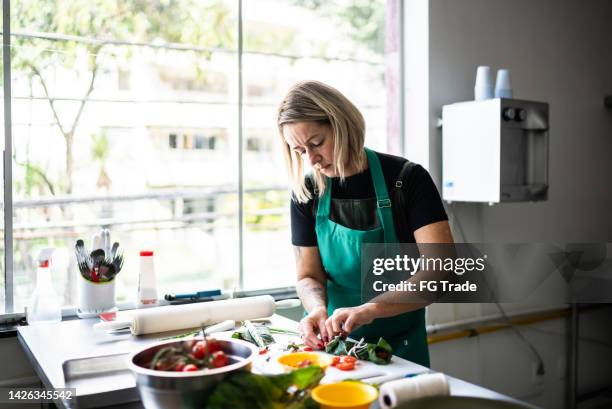 fokussierte frau, die eine mahlzeit zubereitet - köchin stock-fotos und bilder