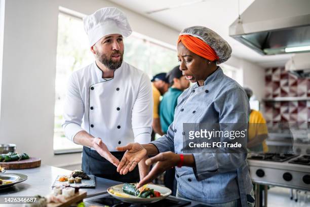 colleagues arguing about a dish in the kitchen - rich fury stock pictures, royalty-free photos & images