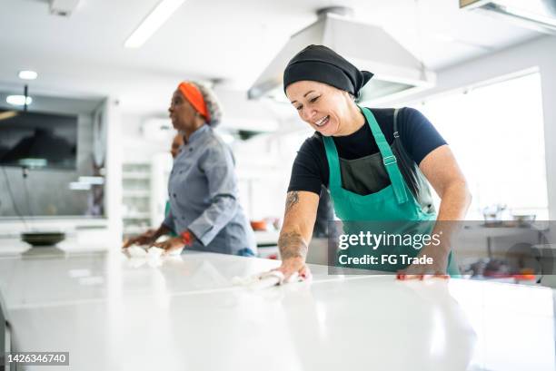 mature woman cleaning kitchen counter at commercial kitchen - restaurant cleaning stock pictures, royalty-free photos & images