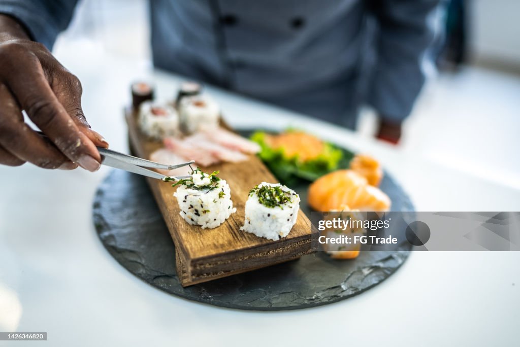 Hände des Küchenchefs legen Sushis in einen Teller