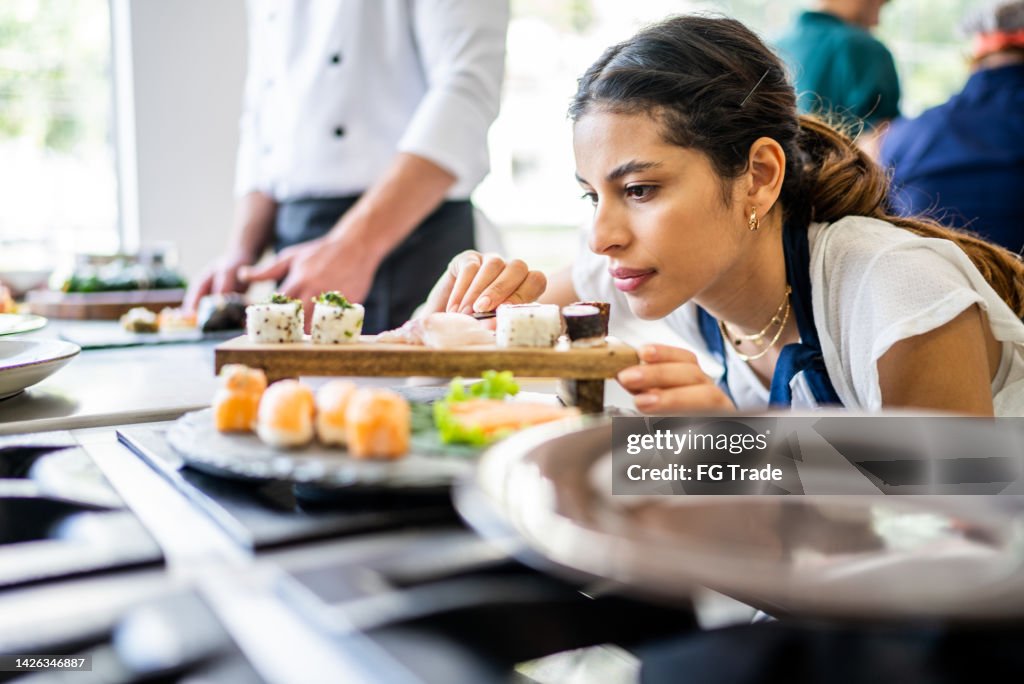 Junge Frau bereitet Sushi in der Küche zu