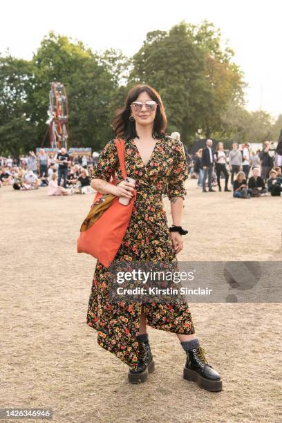 Amy Strode wears Dr Martens boots, vintage dress and scarf, New Look sunglasses at Victoria Park on August 28, 2022 in London, England.