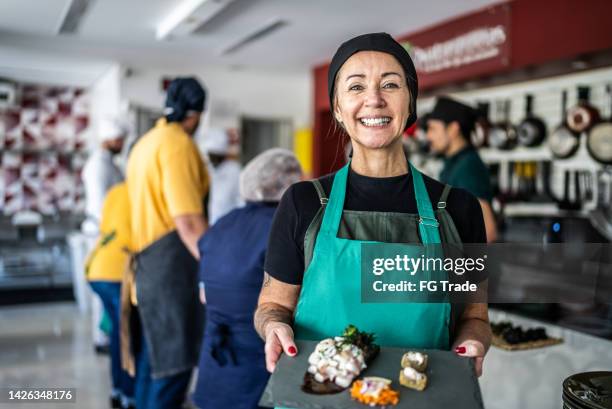 mature woman showing a meal she'd prepared in a cooking class - cookery class stock pictures, royalty-free photos & images