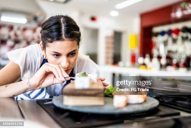 young woman preparing sushis at the kitchen - sushi chef stock pictures, royalty-free photos & images