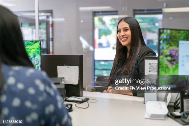 smiling customer at reception desk - bankpersoneel stockfoto's en -beelden