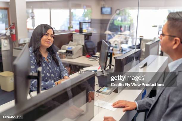 cheerful bank teller assisting a customer - bank office clerks stock pictures, royalty-free photos & images