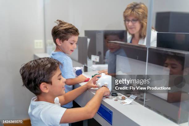 brothers putting money in their savings account - bank office clerks stock pictures, royalty-free photos & images