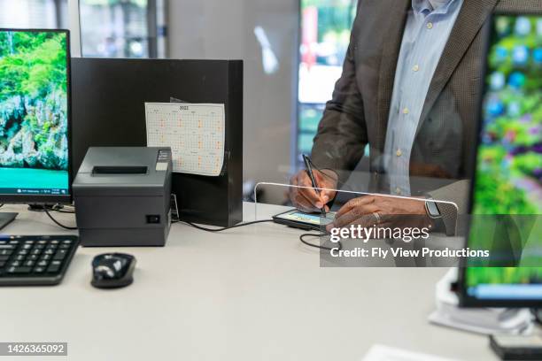 customer signing after making credit card payment - bank office clerks stock pictures, royalty-free photos & images