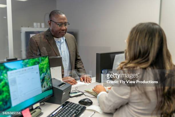 bank teller counting money for customer - bank counter stock pictures, royalty-free photos & images