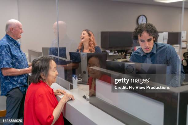senior man and woman at business reception desk - busy hospital lobby stockfoto's en -beelden