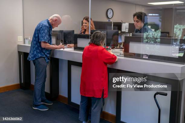 senior man and woman at business reception desk - banco imagens e fotografias de stock