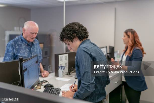 réceptionniste masculin aidant un client - banque accueil photos et images de collection