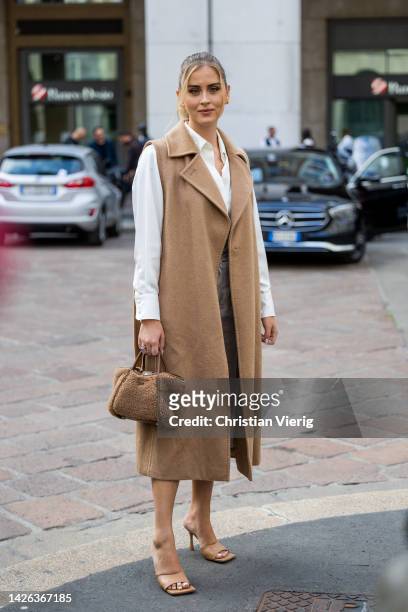 Valentina Ferragni wears beige sleeveless coat, teddy bag, white button shirt, grey cropped pants outside Max Mara during the Milan Fashion Week -...