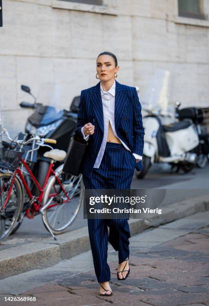 Guest wears navy striped suit, white button shirt, black bag, sandals outside Max Mara during the Milan Fashion Week - Womenswear Spring/Summer 2023...