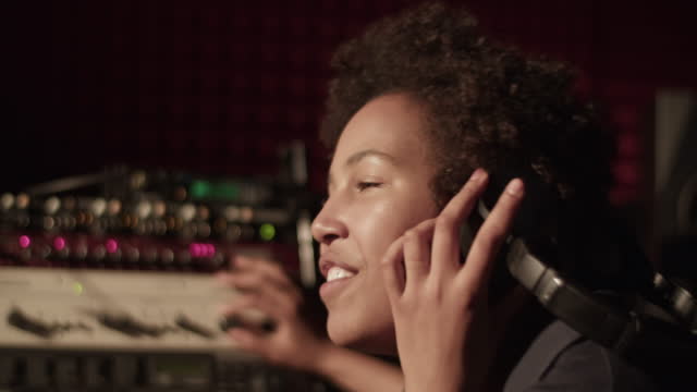 Happy black woman singing near soundboard