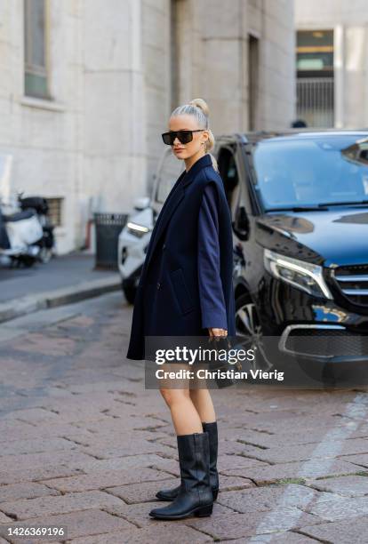 Victoria Magrath with pigtail wears sleeveless double breasted navy jacket, black mid knee high boots, bag, sunglasses outside Max Mara during the...