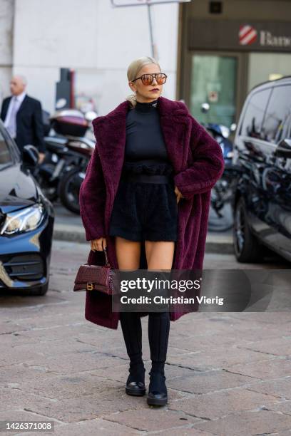 Caroline Daur wears burgundy Balenciaga bag, navy high waisted belted fleece skirt, black turtleneck, teddy coat, black over knees boots, sunglasses...