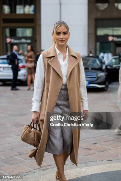 Valentina Ferragni wears beige sleeveless coat, teddy bag, white button shirt, grey cropped pants outside Max Mara during the Milan Fashion Week -...