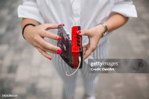 close-up of a woman's hands putting a cassette into a personal stereo - personal stereo stockfoto's en -beelden