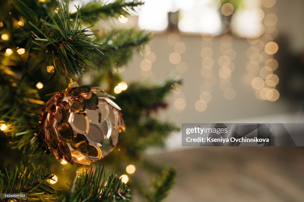 Christmas, New Year interior with red brick wall background, decorated fir tree with garlands and balls, dark drawer and deer figure