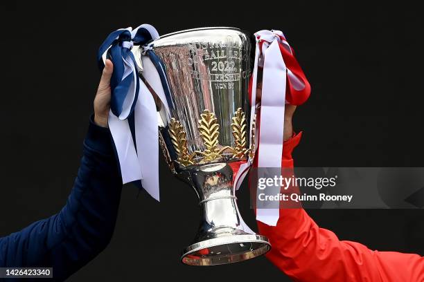 The 2022 Premiership Trophy is held aloft by Joel Selwood of the Geelong Cats and Luke Parker of the Sydney Swans during the 2022 AFL Grand Final...