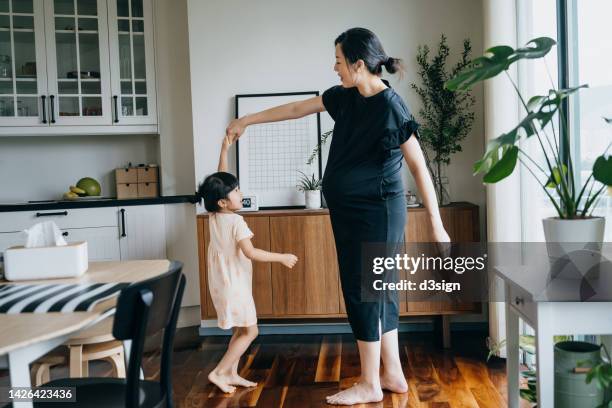happy young asian pregnant mother having fun dancing with her lovely daughter at home. mother and daughter spending time together. bonding between mother and daughter. family fun lifestyle - very young asian girls ストックフォトと画像