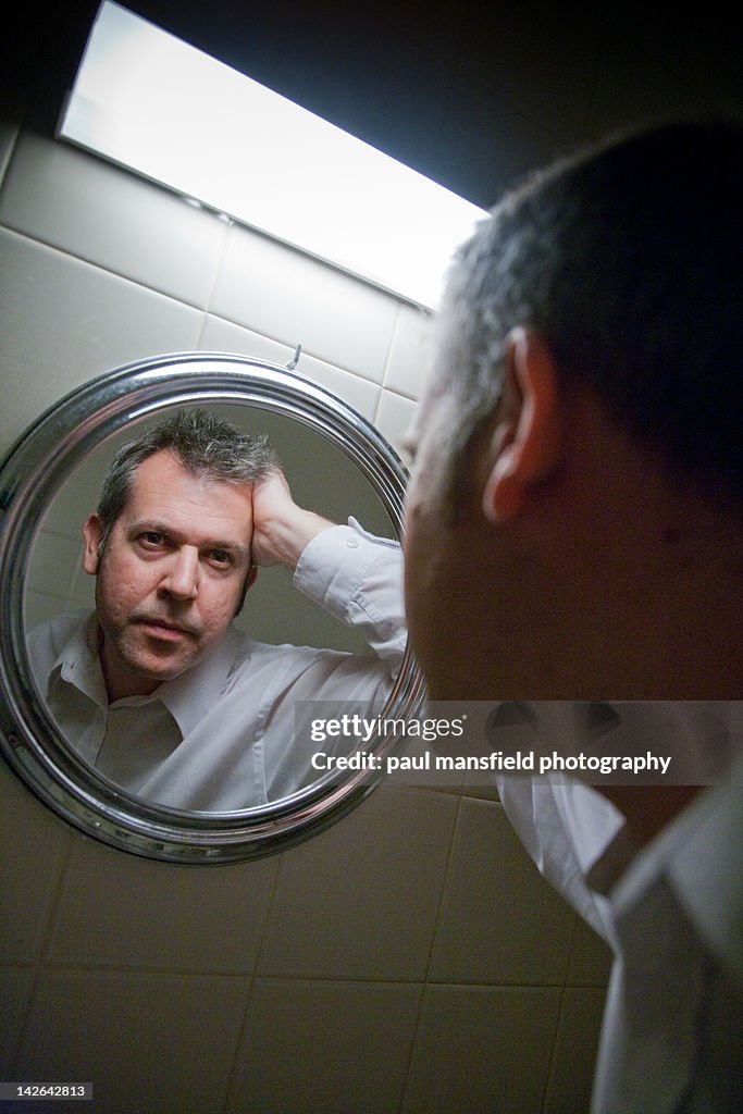 Man stares into bathroom mirror