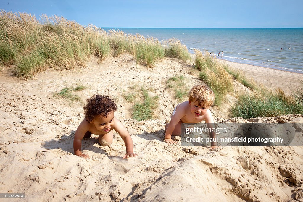 Two toddlers playing on sand dunes