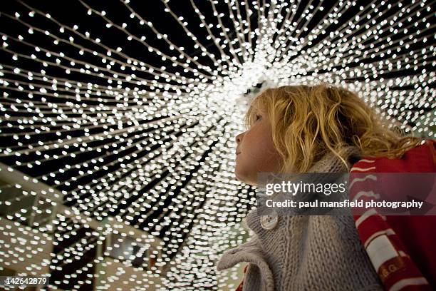 girl looking upwards at fairy lights - cadena de luces fotografías e imágenes de stock