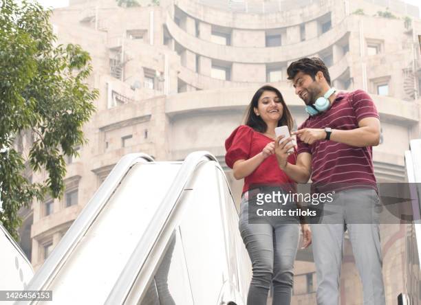 happy couple using mobile phone outdoors in city - india couple lift stock pictures, royalty-free photos & images