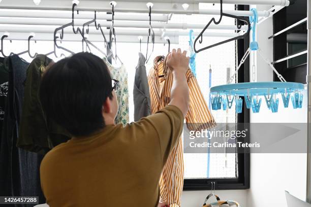 singaporean man hanging his laundry to dry at home - clothesline ストックフォトと画像