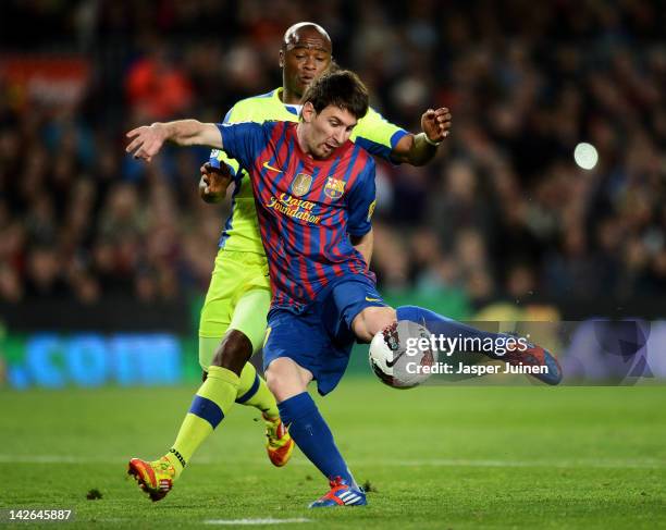 Lionel Messi of FC Barcelona shoots on goal while he duels with Tshepo Masilela of Getafe during the La Liga match between FC Barcelona and Getafe CF...