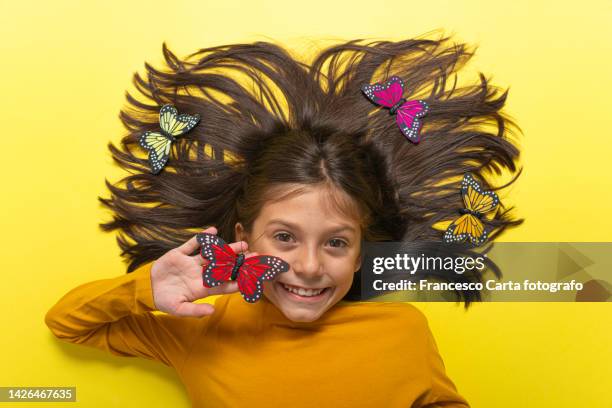 smiling little girl with fake butterflies - fake-butterflies stock pictures, royalty-free photos & images