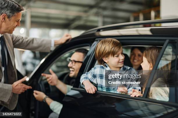 glückliche familie wählt ein neues auto in einem showroom. - car ownership stock-fotos und bilder