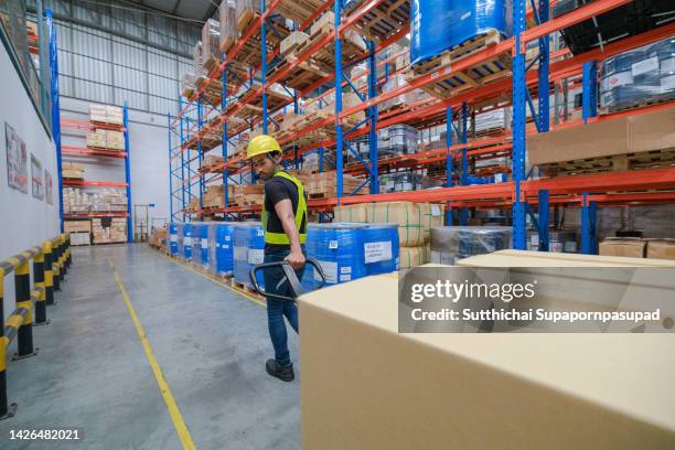 asian male worker pushing an hydraulic hand pallet truck on a warehouse. - chonburi province stock photos et images de collection