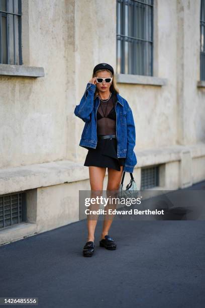 Maja Malnar wears a black puffy headband from Prada, silver earrings, white sunglasses from Prada, a silver necklace, a black transparent t-shirt, a...