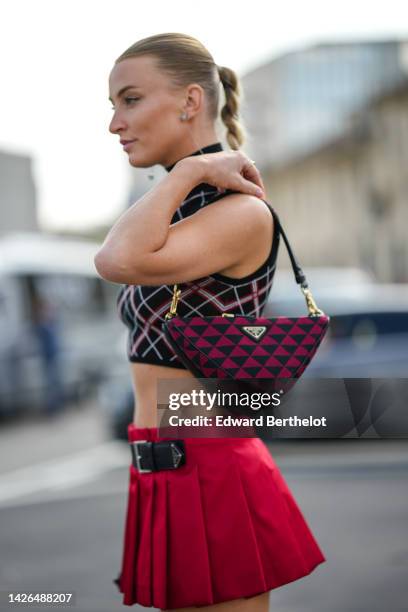 Noor de Groot wears silver pendant earrings from Prada, a black with red and white checkered print pattern turtleneck / sleeveless / cropped top from...