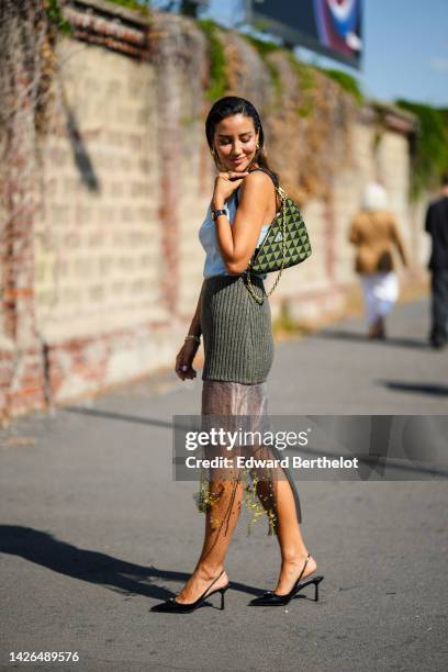 Tamara Kalinic wears gold earrings , a pale blue tank-top from Prada, a half khaki ribbed wool / half tulle with embroidered yellow pattern midi...