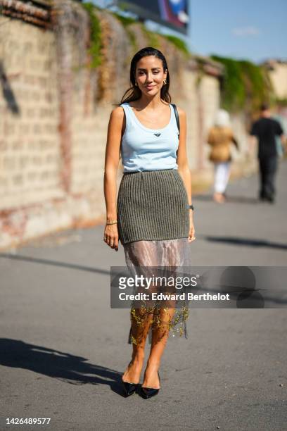 Tamara Kalinic wears gold earrings , a pale blue tank-top from Prada, a half khaki ribbed wool / half tulle with embroidered yellow pattern midi...