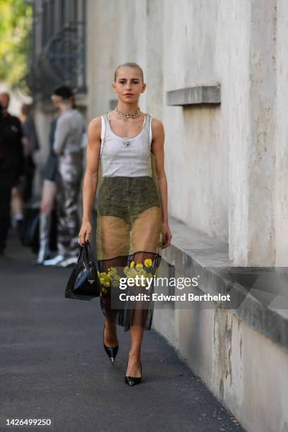 Caroline Daur wears gold and silver large necklaces, a white tank-top from Prada, a gold transparent with black tulle with embroidered yellow flower...