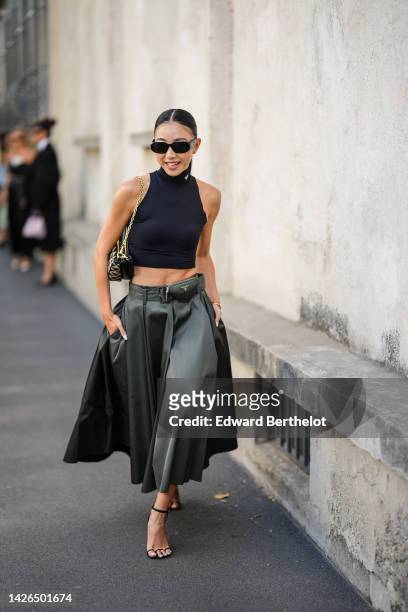 Yuwei Zhangzou wears black sunglasses from Prada, a black turtleneck / sleeveless / top from Prada, a beige and black triangular print pattern fabric...
