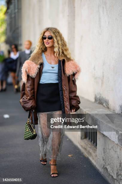 Emili Sindlev wears a green and black triangular print pattern with black shiny leather Triangle handbag from Prada, black sunglasses, gold earrings,...